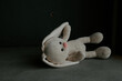 Concept: lost childhood, loneliness, pain and depression. Plush bunny lying down in a room.