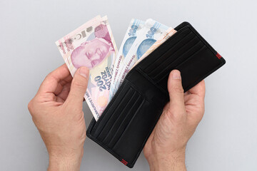 Wall Mural - Male hand holding wallet with Turkish lira. Gray background.