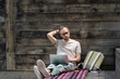 © DimaBerlin - Focused man remote worker in eyewear working on laptop remotely outside, sitting on wooden staircase at outdoor workspace. Pensive european guy student following online lectures and enjoying open air