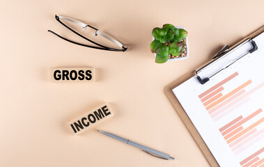 Poster - GROSS INCOME text on wooden block with chart and glasses, business concept