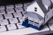 Miniature white house sitting on a white computer keyboard real estate vacation rental home