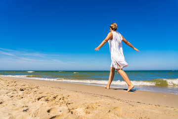 Wall Mural - Woman walking on sunny beach
