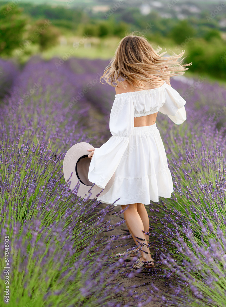 Portrait of a beautiful young girl in a white summer dress and hat in a ...