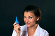 cheerful beautiful nurse with an enema in her hand smiles mysteriously on a black background