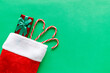 Christmas stocking with gift box and candy canes on green background.