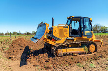 Side View Working Bulldozer Clears The Area Before Construction. Blue Sky Background.