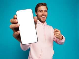 Wall Mural - handsome excited man showing pointing at empty smartphone screen posing over light blue background, 