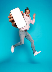Wall Mural - handsome excited man showing pointing at empty smartphone screen posing over light blue background, 