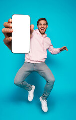 Wall Mural - handsome excited man showing pointing at empty smartphone screen posing over light blue background, 