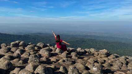 Young woman enjoying beautiful sunrise sky on the mountain.