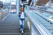 © Valerii Honcharuk - Woman with backpack walking up the stairs near escalator in modern station building