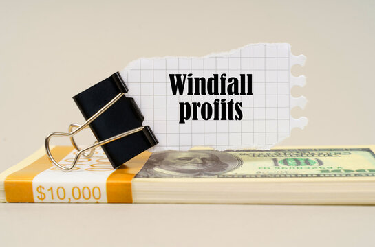 There are dollars on the table, on which there is a clip and torn paper with the inscription - Windfall profits