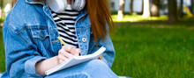 Unrecognizable Girl Takes Down Notes In Notebook In The Park.Distant Learning. University,college,school Education