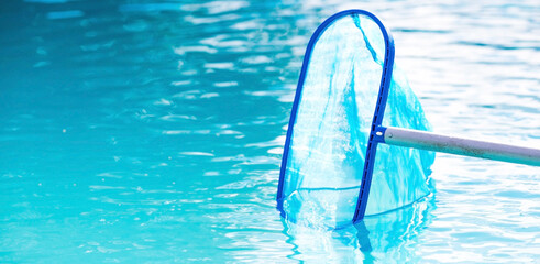 Cleaning a swimming pool with a metal frame with a net from leaves and dirt. Pool cleaner during work. Solar banner. The concept of summer holidays.