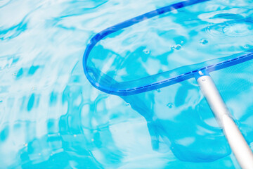 Cleaning a swimming pool with a metal frame with a net from leaves and dirt. Pool cleaner during work. Solar banner. The concept of summer holidays.