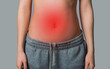 woman's stomach with redness on gray background. stomach problems concept