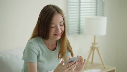 Wall Mural - Young Caucasian woman use mobile phone chat on bed at home in morning.