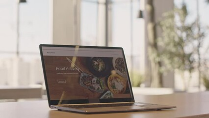 no people shot of food delivery website on laptop screen on table in bright spacious room with panor