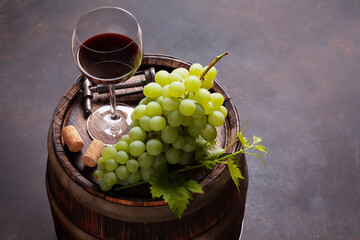 Wall Mural - Red wine glass and white grape on old barrel