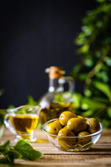 Poster - Green olives fruits in olive oil on wooden table
