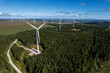 © mark_gusev - Aerial view on a wind electricity generator in a forest area of Connemara, county Galway, Ireland. Production of clean renewable energy. Industrial object in nature environment. Blue cloudy sky
