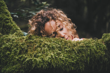 People enjoy and love feeling with green nature. Serene woman have relax and rest with face on a green soft musk trees trunk. Love outdoors park and leisure activity. Beautiful female touching nature