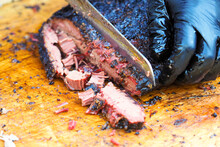 Cutting The Finished Brisket With A Knife. Brisket Bbq Smoked Beef Sincled In Foil