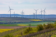 Landschaft mit Weinreben und Feldern vor unzähligen Windkraftanlagen am Horizont in Rheinland-Pfalz
