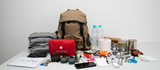 emergency backpack equipment organized on the table. documents, water,food, first aid kit and anothe