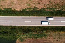 Aerial Shot Of Two White Van Vehicles Passing By Each Other On Highway Through Countryside Landscape On Sunny Summer Day