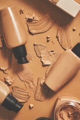 Bottles of makeup foundation and samples on beige background