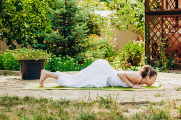 Young woman practices yoga in the garden. Surya namaskar, Four-point pose, Ashtanga Namaskar, or greeting with eight body parts