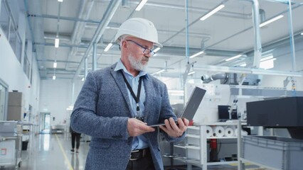 Aufkleber - Portrait of a Bearded Middle Aged General Manager Walking in a Factory Facility, Wearing Casual Suit and a White Hard Hat. Heavy Industry Specialist Working on Laptop Computer.
