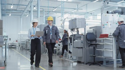 Poster - Two Diverse Young Heavy Industry Engineers in Hard Hats Walking with Laptop Computer and Talking in a Factory. Two Manufacturing Employees at Work in Research and Development Facility.