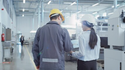 Fototapete - Two Young Asian Heavy Industry Engineers Walking with Their Backs to Camera, Using Laptop Computer, Discussing Production of a New Component. Two Employees at Research and Development Factory.