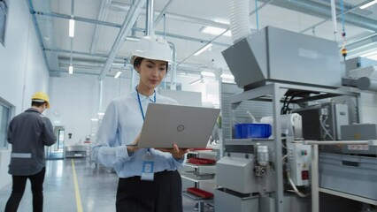 Poster - Portrait of an Asian Female Engineer in Hard Hat Walking and Using Laptop Computer at Electronic Manufacturing Factory. Technician Working on Daily Tasks and Research and Development Data.