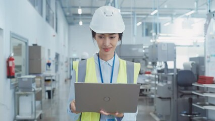 Fototapete - Portrait of a Happy Asian Female Engineer in Hard Hat Standing and Using Laptop Computer at Electronic Manufacturing Factory. Technician Working on Research and Development Production Plan.