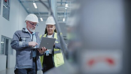 Aufkleber - Two Heavy Industry Employees in Hard Hats Discussing Job Assignments at the Factory, Using Laptop Computer. African American Engineer and Middle Aged Technician at Work.