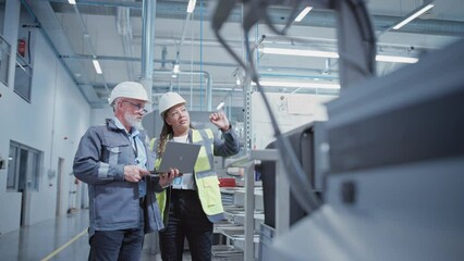 Poster - Portrait of Two Heavy Industry Employees in Hard Hats at Factory. Checking and Discussing Industrial Facility, Using Laptop Computer. African American Engineer and Middle Aged Technician at Work.