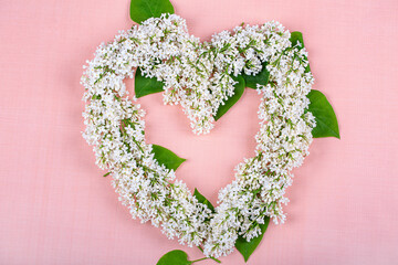 Wall Mural - A heart of white lilac flowers on a pink background, copy space