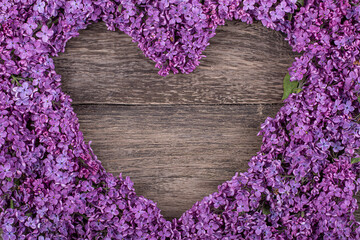 Wall Mural - heart of purple lilac flowers on an old wooden background, copy space
