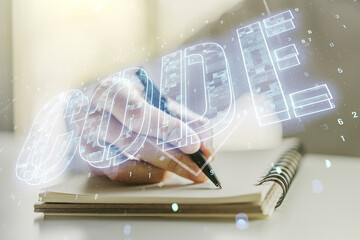 Poster - Creative Code word hologram and man hand writing in notepad on background, artificial intelligence and neural networks concept. Multiexposure