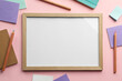 Blank white board with stationery on light pink background, flat lay. Space for text
