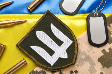 ukrainian army chevron near camouflage fabric, bullets and military id tags on national flag of ukra