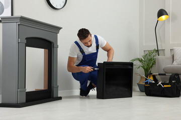 Poster - Professional technician with screwdriver installing electric fireplace in room