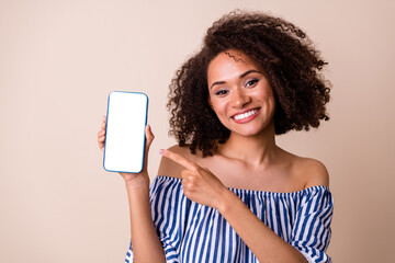 Portrait of gorgeous lady indicate finger hand hold telephone empty space screen isolated on beige color background