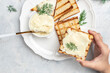 © Надія Коваль - Female hands holding Sliced bread with cream cheese and butter for breakfast. melted cheese sandwich on light background. Food recipe background. Close up