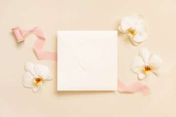 Wall Mural - Wedding envelope near white orchid flowers and silk ribbons on light yellow, suite mockup