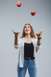 Young beautiful woman juggles with a red apple on a white background. Healthy lifestyle