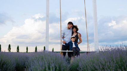 Family with a child on a swing in the middle of a lavender field